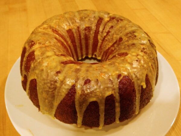 A bundt cake drizzled with orange frosting