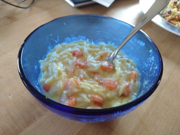 A bowl of creamy orzo lemon soup with carrot coins