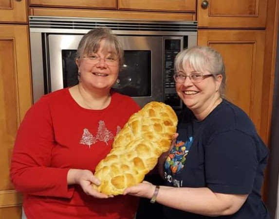 Two women holding a large plaited loaf of bread